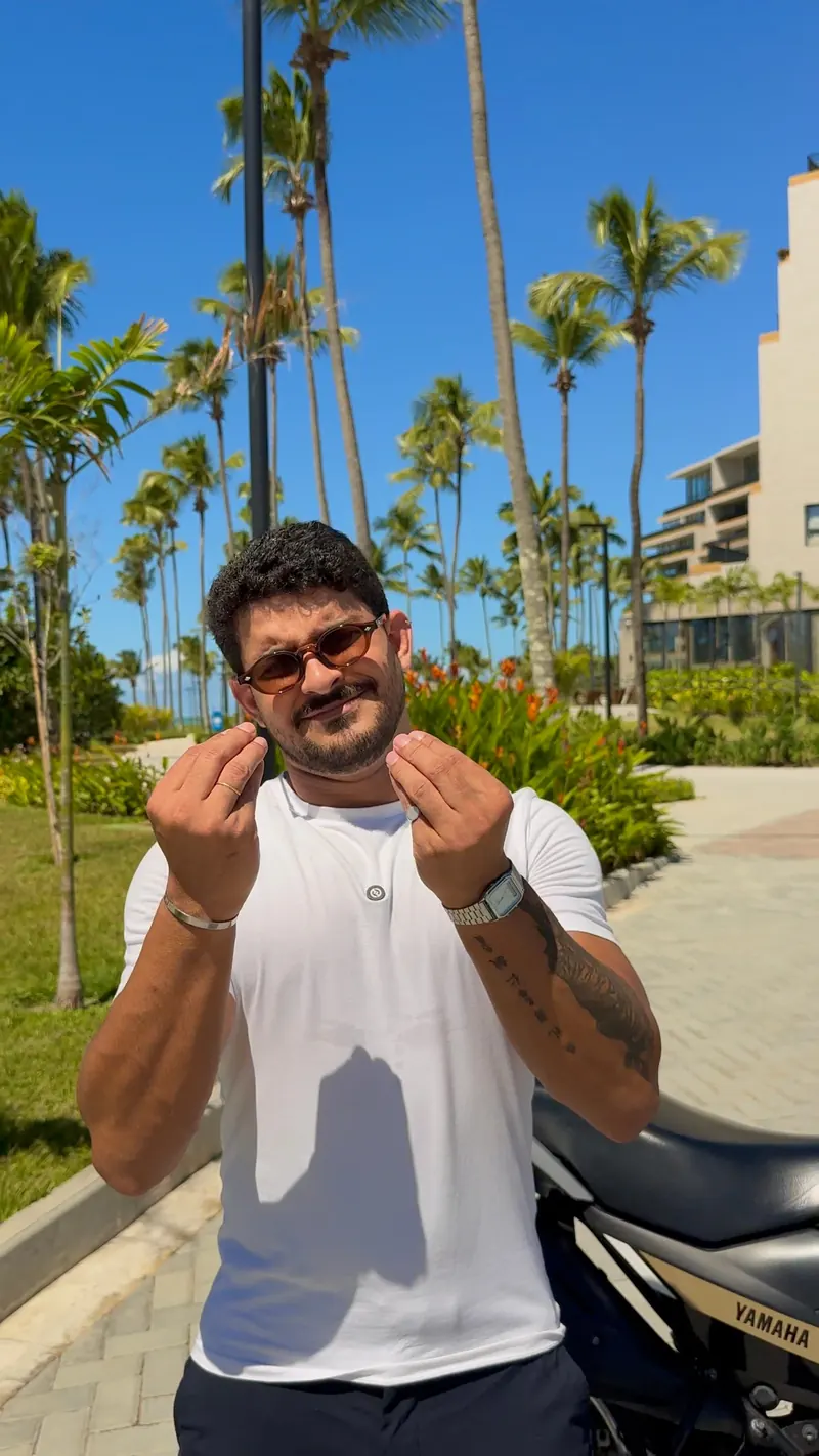 Victor fazendo sinal de dinheiro ao lado da moto