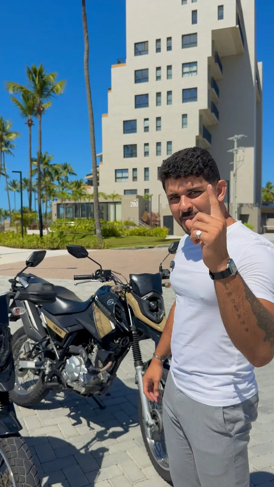 Victor apontando para quem está vendo, ao lado de uma Yamaha Crosser